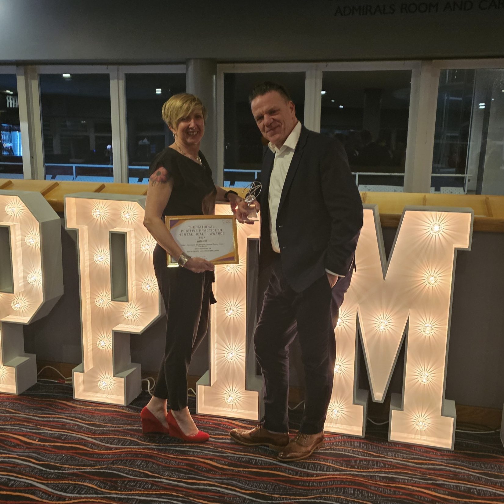 CREST staff stood in front of giant letters, reading PPIMH, to stand for Positive in Practice Mental Health awards, at the award ceremony.