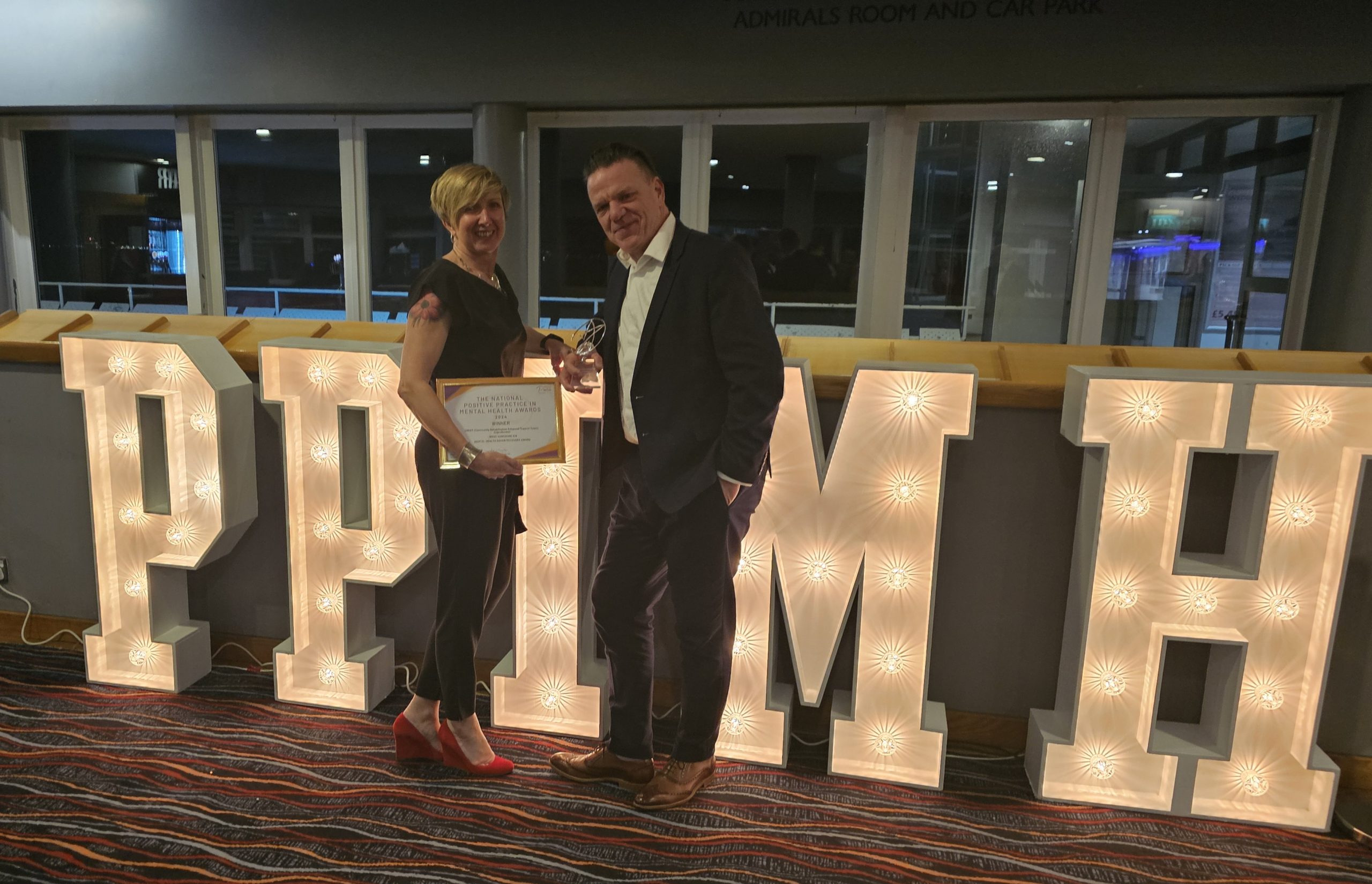 CREST staff stood in front of giant letters, reading PPIMH, to stand for Positive in Practice Mental Health awards, at the award ceremony.